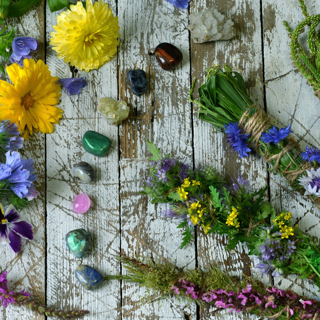 Top view of herbs, flowers and reiki crystals on wooden witch table.