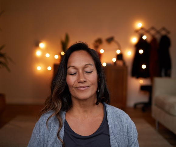 Serene mature woman smiling while meditating at home
